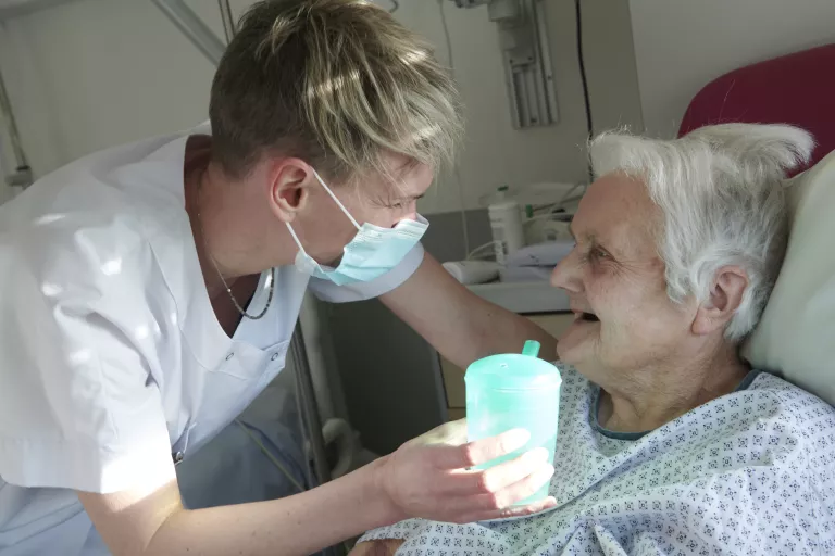 soignante donne à boire à une personne âgée